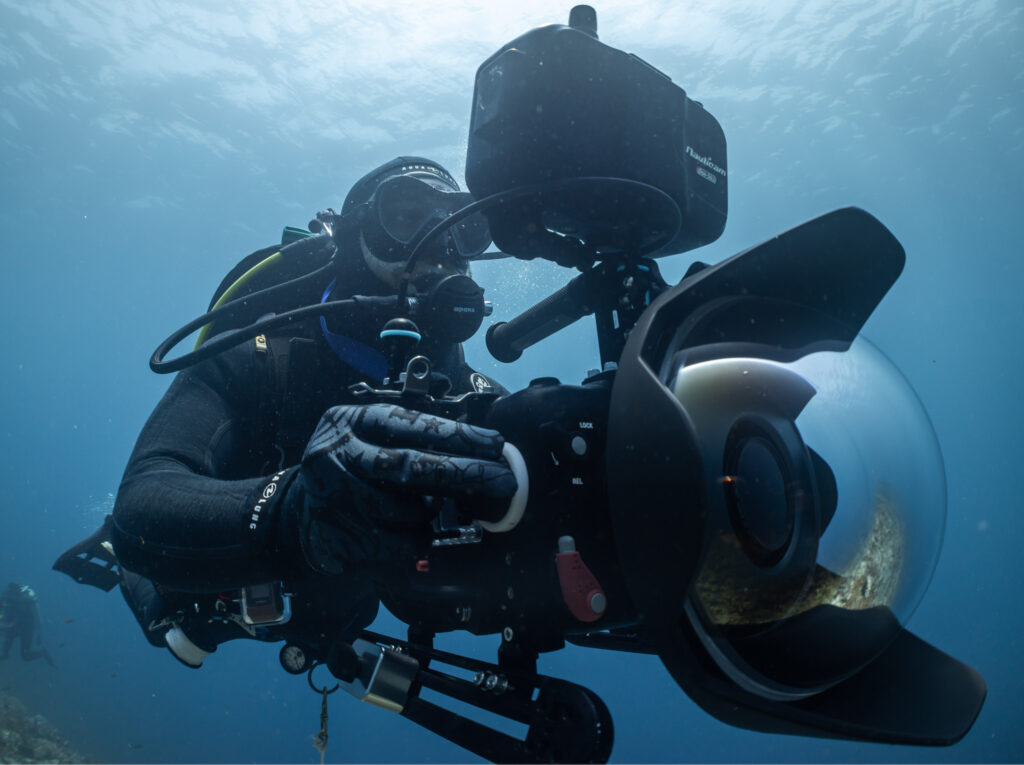 Underwater camera operator in diving equipment with a cinema camera housing